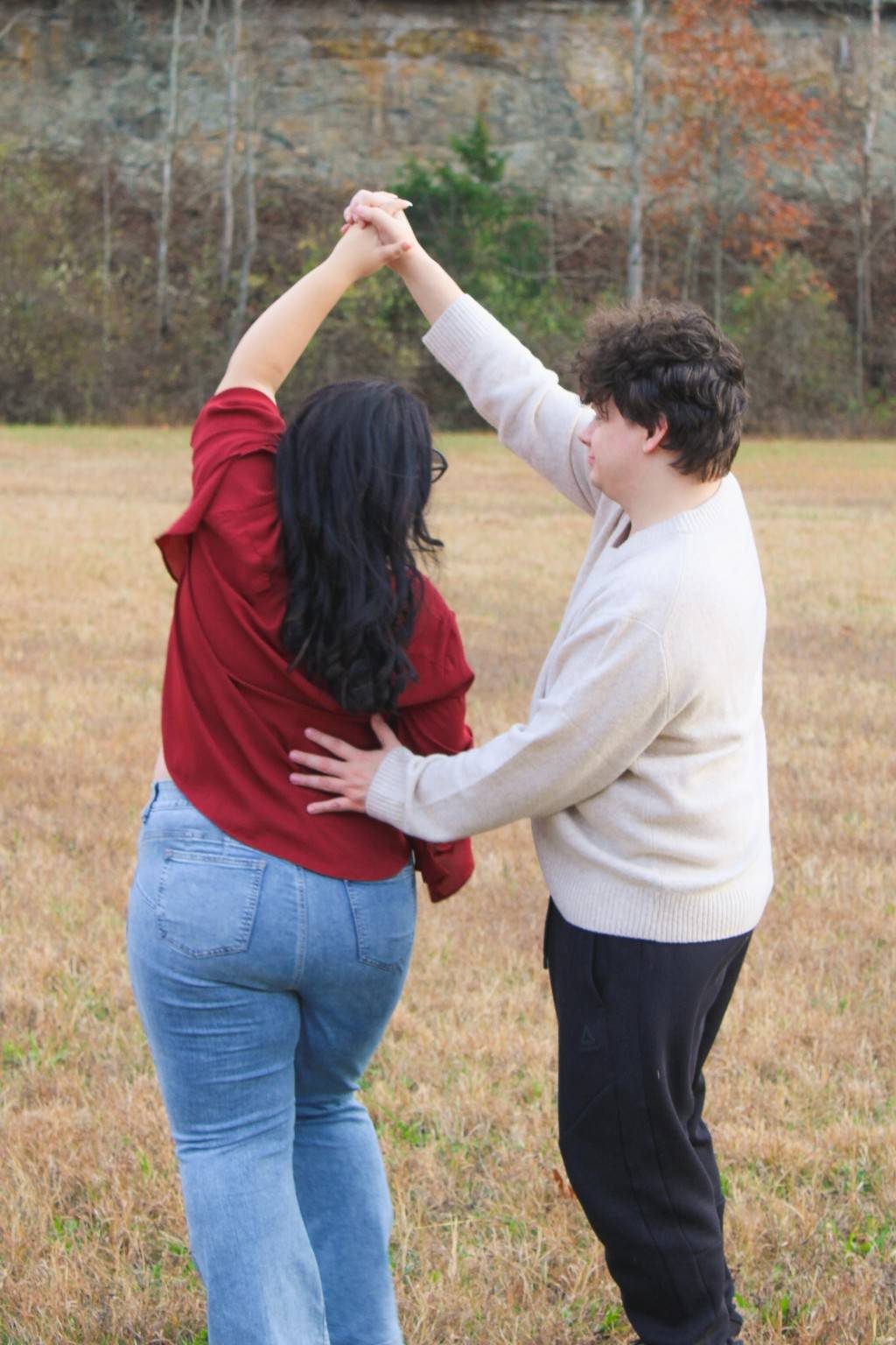 Briana and Ryan holding hands and dancing in a grassy field